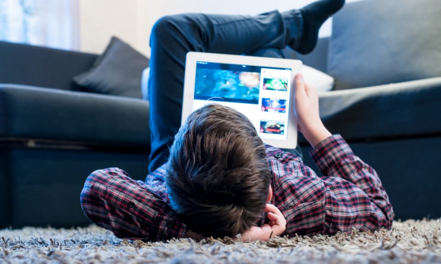 teenager with tablet while lying on the floor in the room