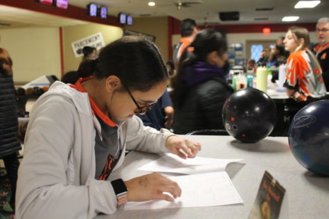 Sophomore Jasmine Keene checks the rankings sheet before the match starts. The ranking sheet shows where the different teams and players rank compared to one another.