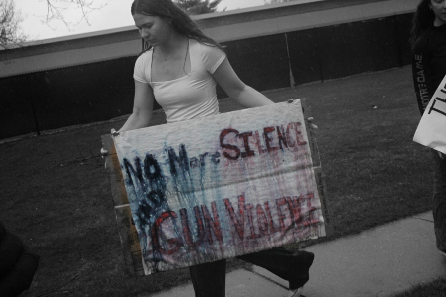Junior Anna Wiltzer braves the wind and rain with her homemade sign to protest gun violence in Wednesdays student walk out. 