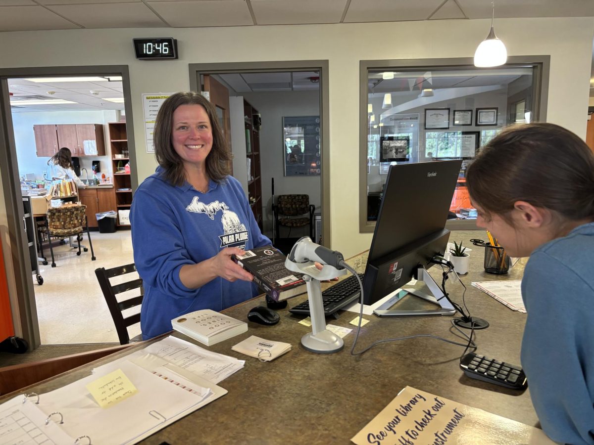 Librarian Megan Hall checks out a book for senior Abby Sherrill.